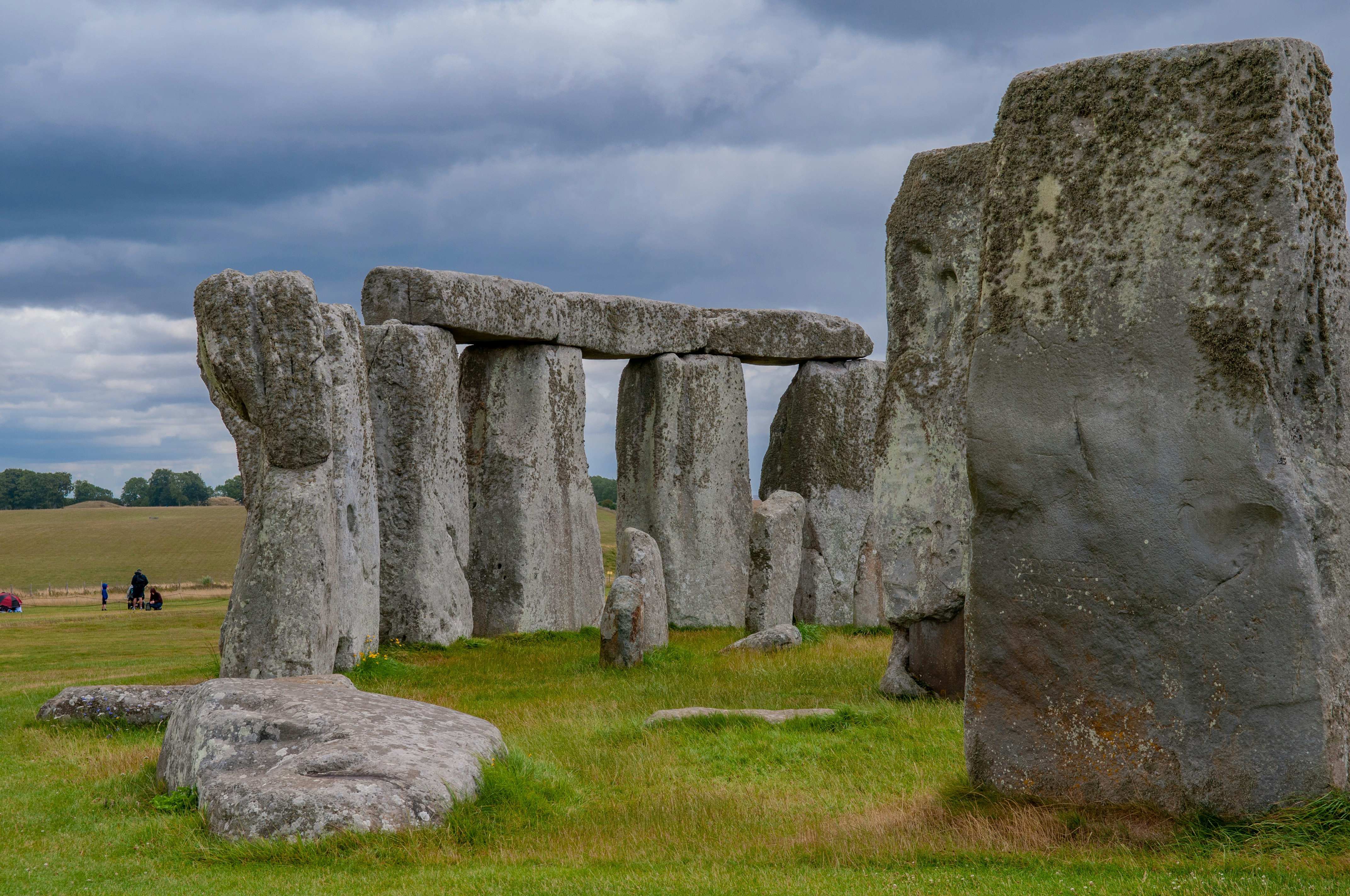 gray rock formation on green grass field under white clouds and blue sky during daytime